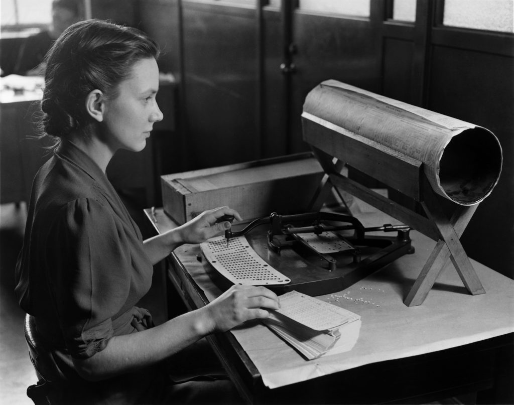 Black and white photo of a woman using a keypunch to tabulate the United States Census, circa 1940.